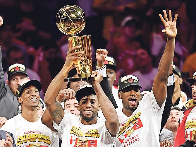 Toronto Raptors forward Kawhi Leonard, center, holds Larry O’Brien NBA Championship Trophy after the Raptors defeated the Golden State Warriors 114-110 in Game 6 of basketball’s NBA Finals, Thursday, in Oakland, Calif. (Frank Gunn/The Canadian Press via AP)