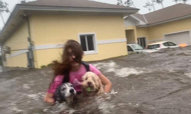 Julia Aylen wades through waist deep water carrying her pet dogs during Hurricane Dorian in Freeport. (AP Photo/Tim Aylen)