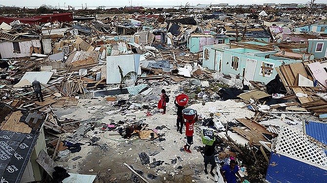 People search for salvageable items as they make their way through an area destroyed by Hurricane Dorian in Marsh Harbour. (Al Diaz/Miami Herald via AP)