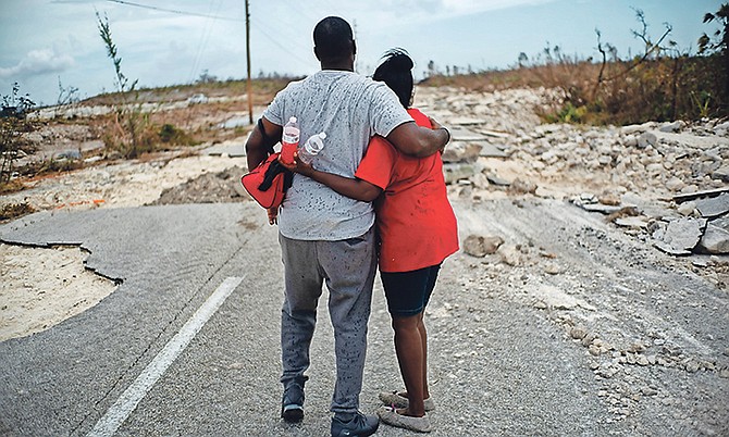 A couple embraces on a road destroyed by Hurricane Dorian as they walk to the town of High Rock to try and find their relatives in the aftermath of Hurricane Dorian in Grand Bahama yesterday. Photo: Ramon Espinosa/AP