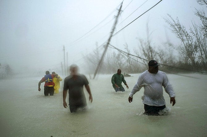 Volunteers wade through a flooded road against wind and rain caused by Hurricane Dorian to rescue families near the Causarina bridge in Freeport on Tuesday. (AP)