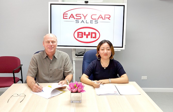 John Farmer, Director of Easy Car Sales, signs an agreement with Neva Zhang, representative for BYD, the largest producer of 100% electric vehicles in the world, to offer their complete range of products and post-sales support in The Bahamas.