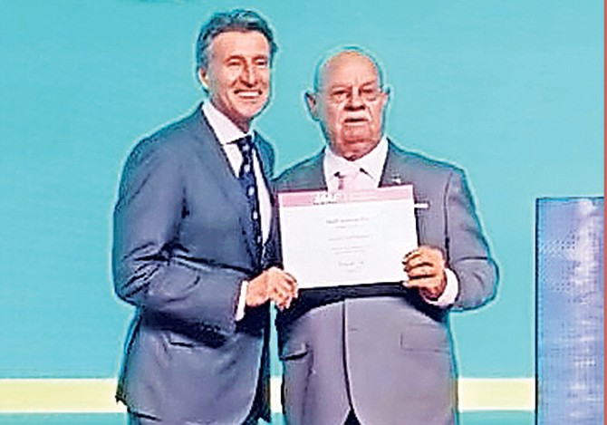 Coach Ronald Cartwright receives his certificate from Sebastian Coe, president of the IAAF.