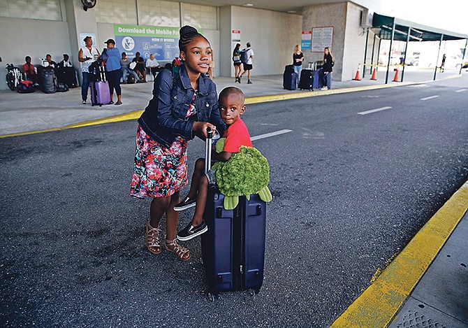 Hurricane Dorian evacuee Kennecia Burrows, 11, pushes her three-year-old cousin, Trevanti Saunders, both of Freeport, across the street as he sits on a suitcase after arriving on the Grand Celebration cruise ship from Freeport, Grand Bahama, on Wednesday of last week in Riviera Beach. The cruise ship transported hundreds of evacuees seeking passage from Freeport after the damage caused by Hurricane Dorian. Photo: Brynn Anderson/AP