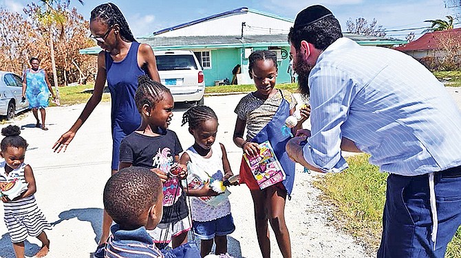 Rabbi Sholom Bluming handing a toy to a child after Hurricane Dorian.