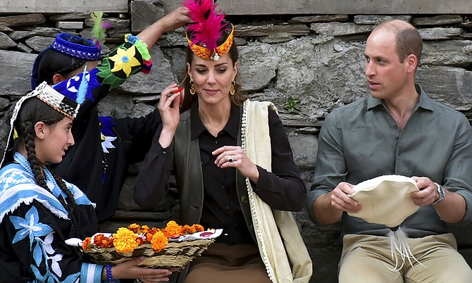 Members of the Kalash community greet Britain's Prince William and his wife Kate with traditional caps during their visit to Bumburate Valley, an area of Pakistan's northern Chitral district, Wednesday Oct. 16, 2019. (Press Information Department via AP)