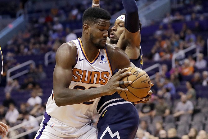 Phoenix Suns centre Deandre Ayton (22) tries to drive past Denver Nuggets forward Torrey Craig during the second half of an NBA preseason basketball game, Monday, in Phoenix. (AP Photo/Matt York)