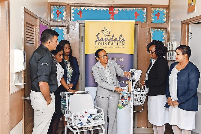 Dr Marcia Bassett of Princess Margaret Hospital (centre) explains to Sandals and hospital staff how the vital sign monitor works.