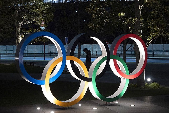 A man is seen through the Olympic rings in front of the New National Stadium in Tokyo, Tuesday.