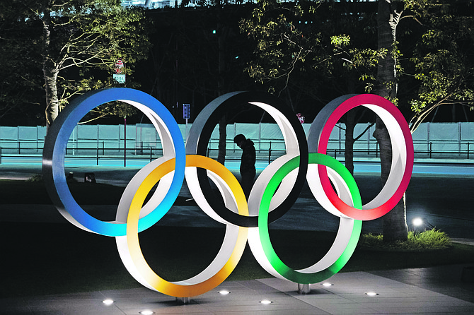 A man is seen through the Olympic rings in front of the New National Stadium in Tokyo yesterday.