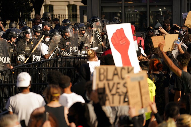 Demonstrators stand in front of police in riot gear as they gather to protest the death of George Floyd, Saturday, near the White House in Washington. Floyd died after being restrained by Minneapolis police officers. (AP Photo/Evan Vucci)