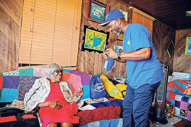 Mable Russell, who is 103 years old, enjoys a visit from Iram Lewis, the Member of Parliament for Central Grand Bahama, at her home in Lewis Yard, West Grand Bahama on Saturday. Mr. Lewis read a letter from Governor General C.A. Smith to the centenarian and conducted a phone call between the Governor General and Ms. Russell. (SURGE Media Photo/Tim Aylen)