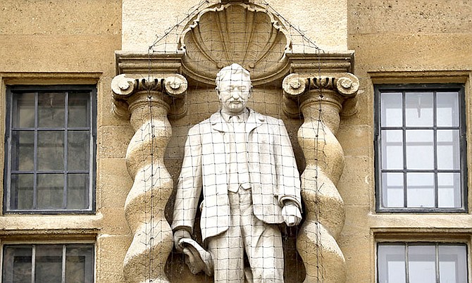 A statue of Cecil Rhodes stands mounted on the facade of Oriel College in Oxford, England.