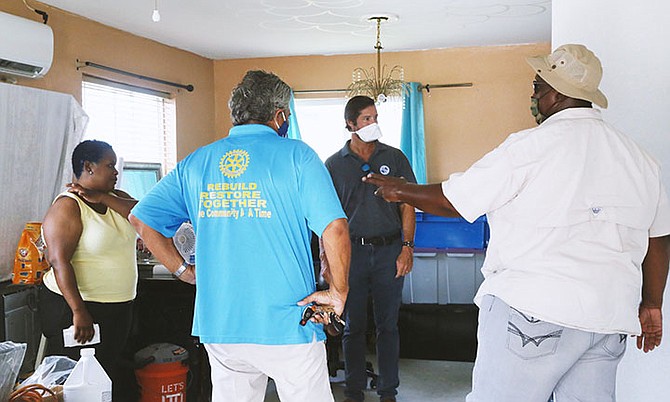 RUPERT HAYWARD, executive director of GBPA, and Rotarian James Sarles with residents of Pioneer’s Loop whose homes were repaired through the GBDRF and Rotary home repair initiative.