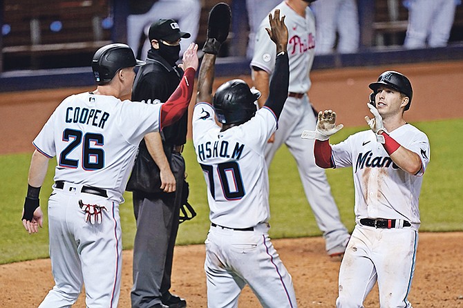 Miami Marlins’ Garrett Cooper (26), Jazz Chisholm (70) and Corey Dickerson, right, celebrate after they scored on a double by Starling Marte during the eighth inning of a baseball game against the Philadelphia Phillies, Thursday, in Miami. (AP Photo/Wilfredo Lee)