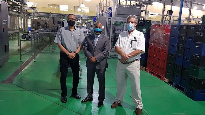 Senator Kwasi Thompson (centre) stands in the newly renovated and expanded warehouse at Bahamian Brewery, during a tour of the facility on Friday. Standing with Mr Thompson is James Sands, president of Bahamian Brewery (right) and Ian Rolle, president of the Grand Bahama Port Authority.  (BIS Photo/Andrew Coakley)