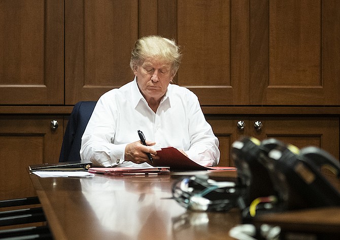 In this image released by the White House, President Donald Trump works in his conference room at Walter Reed National Military Medical Center in Bethesda, Md., Saturday, Oct. 3, 2020, after testing positive for COVID-19. (Joyce N. Boghosian/The White House via AP)