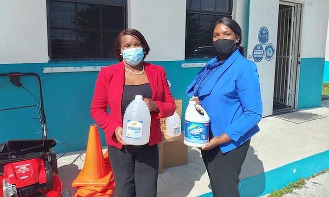 Jackie Russell, left, chairperson of the Pinder’s Point Township, presents a box of hand sanitizers, bleach, a new lawnmower and orange cones to Principal Juanita Hanna of Lewis Yard Primary School.