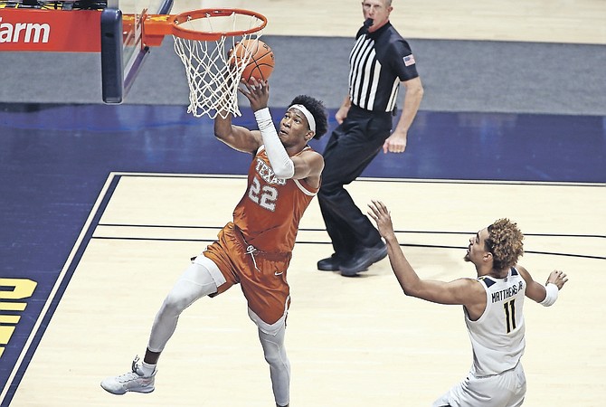 TEXAS forward Kai Jones (22) goes for a score while defended by West Virginia forward Emmitt Matthews Jr. (11) during the second half on Saturday in Morgantown, W.Va.
(AP Photos/Kathleen Batten)