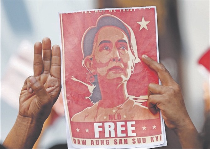 Myanmar nationals living in Thailand hold pictures of Myanmar leader Aung San Suu Kyi gesture with a three-fingers salute, a symbol of resistance, as they protest in front of the Myanmar Embassy in Bangkok, Thailand, yesterday. 
Photo: Sakchai Lalit/AP