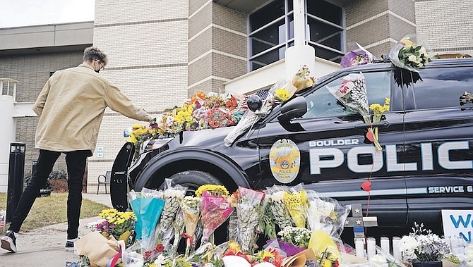 A MAN leaves a bouquet on a police cruiser parked outside the Boulder Police Department after an officer was one of the victims of a mass shooting at a King Soopers grocery store. Photo: David Zalubowski/AP
