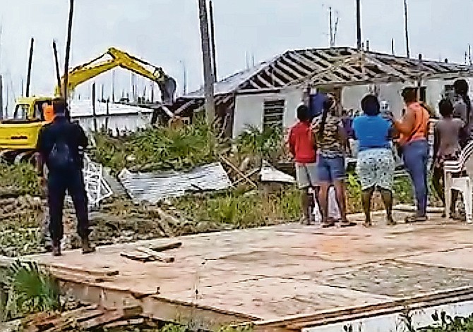 People watch on as the bulldozers move in to tear down buildings in The Farm shanty town in Abaco yesterday, in this image taken from video circulating on social media.