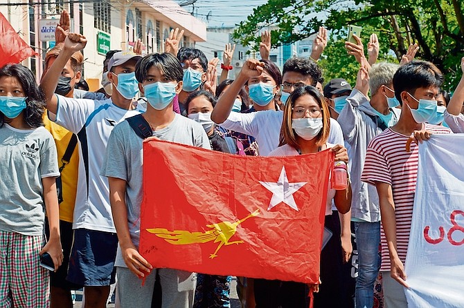 Anti-coup protesters hold the flag of the National League for Democracy party of ousted Myanmar leader Aung San Suu Kyi, while others flash the three-fingered salute during a “flash mob” rally in Bahan township in Yangon, Myanmar, on Sunday.