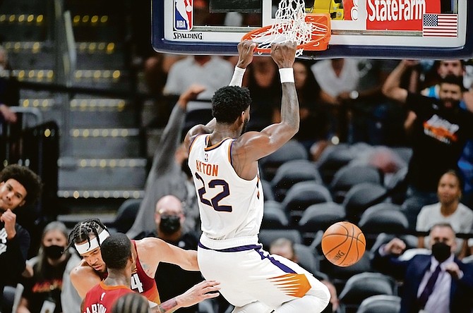 Phoenix Suns centre Deandre Ayton, right, hangs from the rim after dunking the ball as Denver Nuggets forward Will Barton, front left, and centre JaVale McGee defend in the second half last night in Denver.

(AP Photo/David Zalubowski)