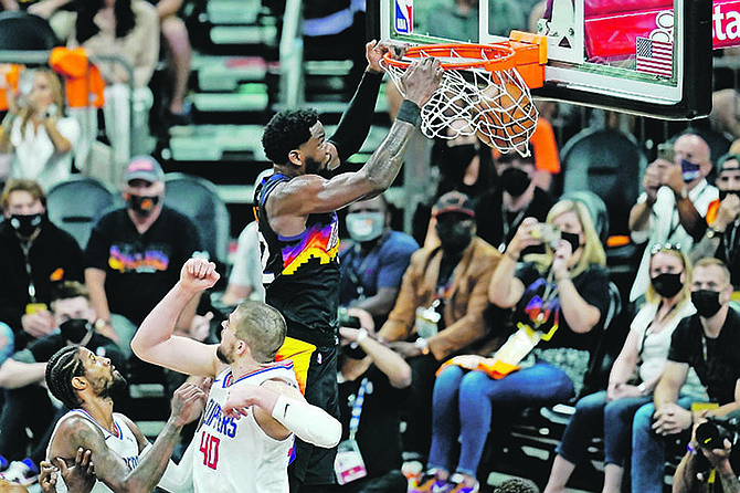 Phoenix Suns centre Deandre Ayton, right, dunks as he gets past Los Angeles Clippers centre Ivica Zubac (40) and guard Paul George, left, during the second half of Game 1 of the Western Conference finals yesterday in Phoenix.

(AP Photo/Ross D Franklin)