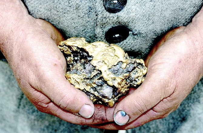 PERSON holding a gold nugget.