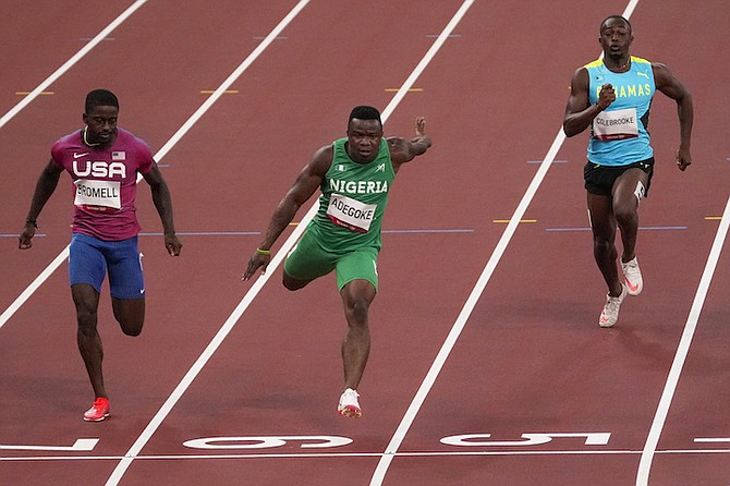 Enoch Adegoke, of Nigeria, centre, wins a heat in the men's 100-metre run at the 2020 Summer Olympics, Saturday in Tokyo. Samson Colebrooke of The Bahamas is on the right. (AP Photo/Charlie Riedel)