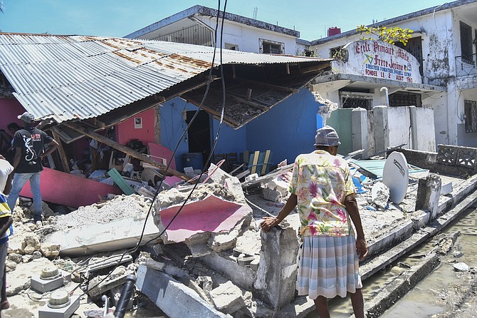 A woman stands in front of a destroyed home in the aftermath of an earthquake in Les Cayes, Haiti, Saturday. (AP Photo/Duples Plymouth)