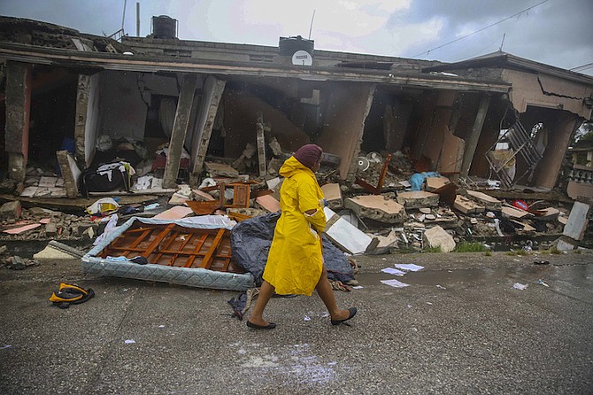 A woman walks in the rain past earthquake-destroyed homes the day after Tropical Storm Grace swept over Les Cayes, Haiti, Tuesday, three days after the 7.2-magnitude earthquake hit. (AP Photo/Joseph Odelyn)