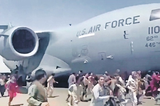 PEOPLE run alongside a US Air Force C-17 transport plane at the international airport, in Kabul, Afghanistan, on Monday.