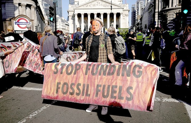 AN EXTINCTION Rebellion climate change activist holds a banner backdropped by the Bank of England, at left, and the Royal Exchange, centre, in the City of London financial district in London earlier
this month. According to a study from University College London climate scientists released on September 8, strict limits on amounts of fossil fuels extracted from the ground are needed to meet climate goals of the Paris Climate Agreement. Photo: Matt Dunham/AP