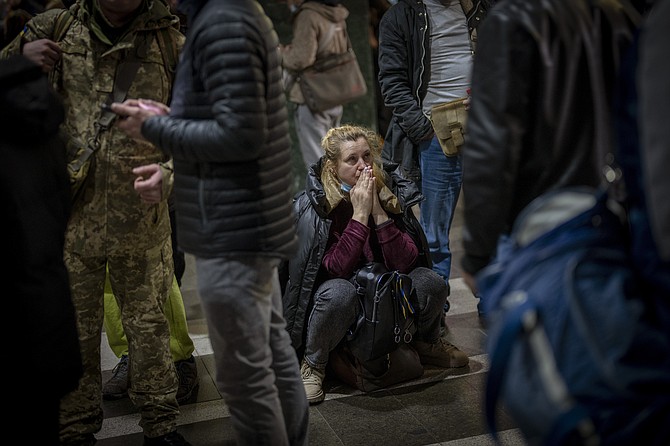 A woman reacts as she waits for a train trying to leave Kyiv, Ukraine, Thursday, Feb. 24, 2022. (AP Photo/Emilio Morenatti)