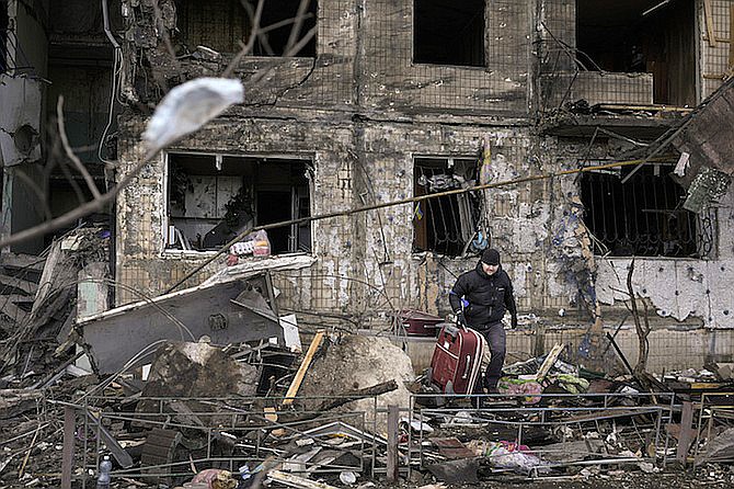 People retrieve belongings from an apartment in a block which was destroyed by an artillery strike in Kyiv, Ukraine, Monday. Russia's military forces kept up their punishing campaign to capture Ukraine's capital with fighting and artillery fire in Kyiv's suburbs Monday after an airstrike on a military base near the Polish border brought the war dangerously close to NATO's doorstep. (AP Photo/Vadim Ghirda)