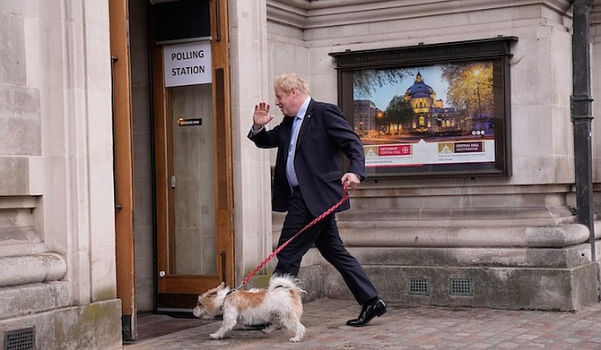 BRITISH Prime Minister Boris Johnson waves at the media as he arrives with his dog Dilyn to vote at a polling station in London, for local council elections on Thursday. Photo: Matt Dunham/AP