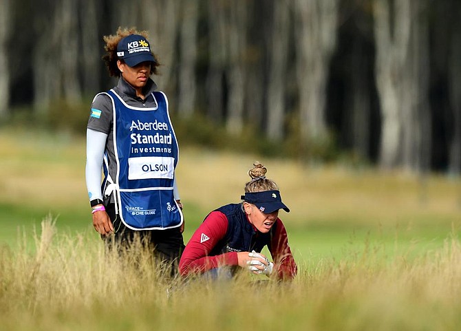 TANEKA, standing, always caddys for Amy Olson, professional golfer, kneeling, with the Bahamian
flag proudly displayed on her gear.