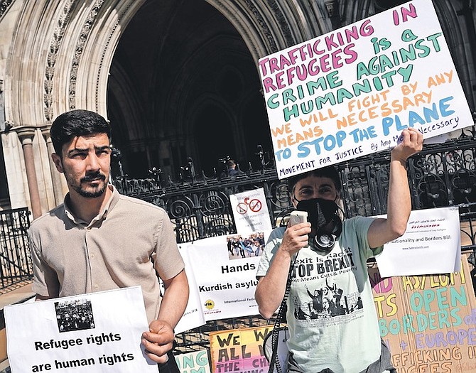 PROTESTERS stand outside the High Court during a ruling on Rwanda deportation flights in London on June 13. Photo: Alastair Grant/AP
