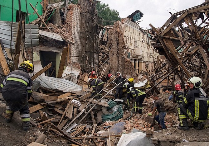 RESCUERS remove debris following a Russian missile attack in Chuhuiv, Ukraine, yesterday. Photo: Evgeniy Maloletka/AP