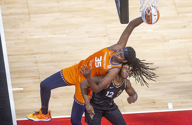 Connecticut Sun forward Jonquel Jones (35) battles for the ball over Las Vegas Aces guard Chelsea Gray (12) during the first half in Game 1 of a WNBA basketball final playoff series Sunday, in Las Vegas. (AP Photo/L.E. Baskow)
