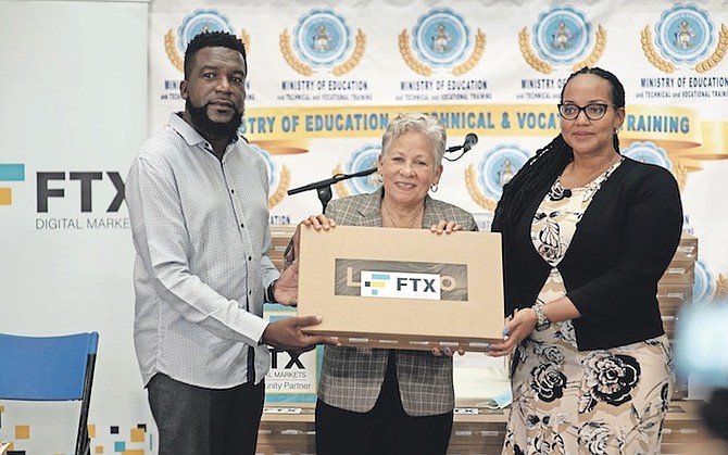 VALDEZ Russell and Zoe Gibson Bowleg, both of FTX, presenting one of the laptops to Education Minister Glenys Hanna Martin. Photo: Moise Amisial