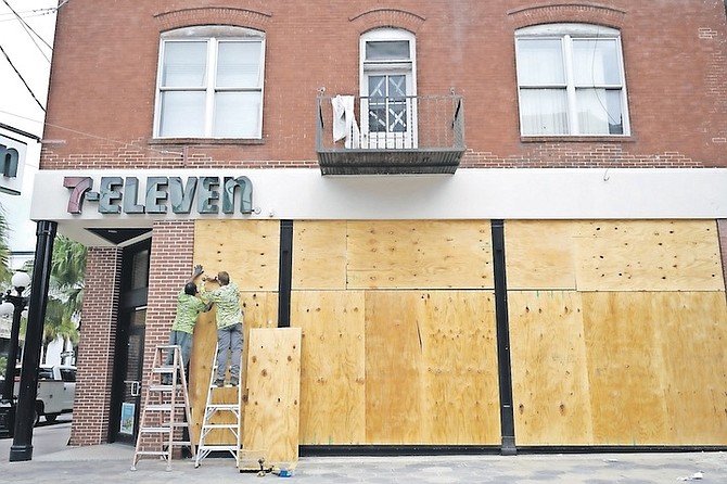 WORKERS board up the windows of a 7-Eleven convenience store in the Ybor City district in preparation for Hurricane Ian as it approaches the western side of the state, in Tampa, Fla. (AP Photo/Phelan M. Ebenhack)