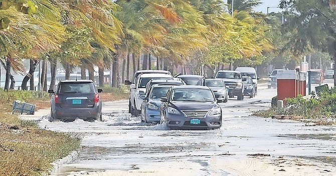 MOTORISTS navigate flooding and debris on West Bay Street yesterday. Photo: Austin Fernander
