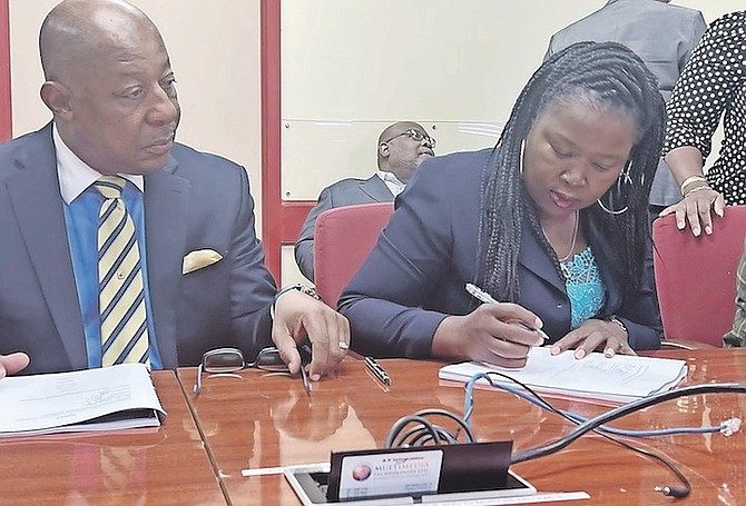 BCPOU president Sherry Benjamin signs yesterday as Bridge Authority chairman Basil Longley watches on. Photo: Letre Sweeting