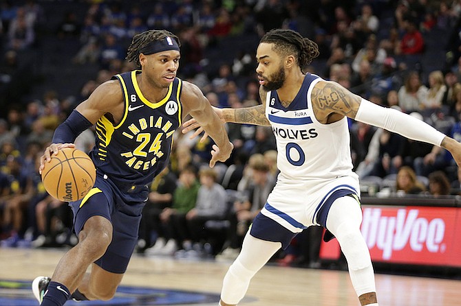 Indiana Pacers guard Buddy Hield (24) drives on Minnesota Timberwolves guard D'Angelo Russell (0) in the third quarter of an NBA basketball game, Wednesday, Dec. 7, 2022, in Minneapolis. (AP Photo/Andy Clayton-King)