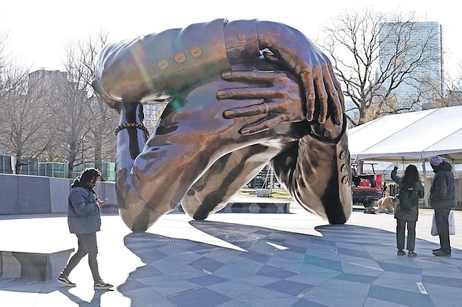 PASSERS-by walk near the 20-foot-high bronze sculpture “The Embrace”, a memorial to Dr Martin Luther King Jr and Coretta Scott King, in the Boston Common, last week, in Boston. The sculpture, consisting of four intertwined arms, was inspired by a photo of the Kings embracing when MLK learned he had won the Nobel Peace Prize in 1964. Photo: Steven Senne/AP