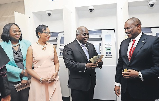 PRIME Minister Philip “Brave” Davis with a handful of money during the opening of the new Bank of The Bahamas branch on John F Kennedy Drive yesterday. Photo: Austin Fernander