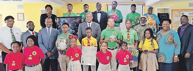 STAFF and scholars of Akhepran International Academy and executive advisors of CYEN showcase symbols such as a globe, a map of the Bahamas Ocean taken from Space by Astronaut Scott Kelly, an eagle, a kente cloth, a mirror, water, a scarab beetle, a plant and a Bible. They are pictured with Environment Minister Vaughn Miller.